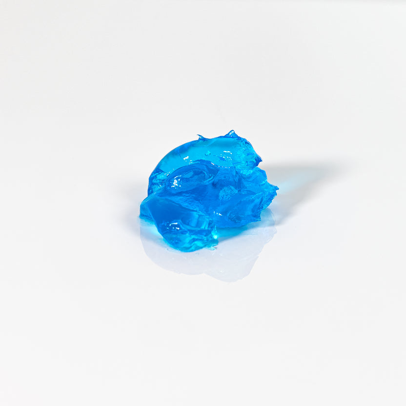A small dollop of translucent bright blue gel or slime on a clean white background with a soft shadow.